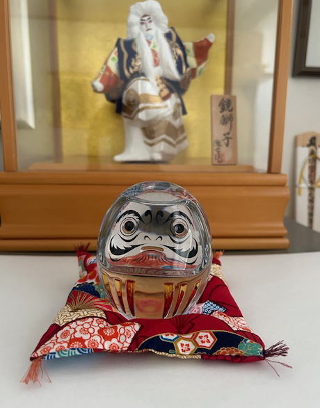 座布団の上に乗っかっているバカラのだるま