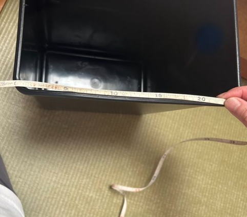 ごみ箱の縁をメジャーで測っています